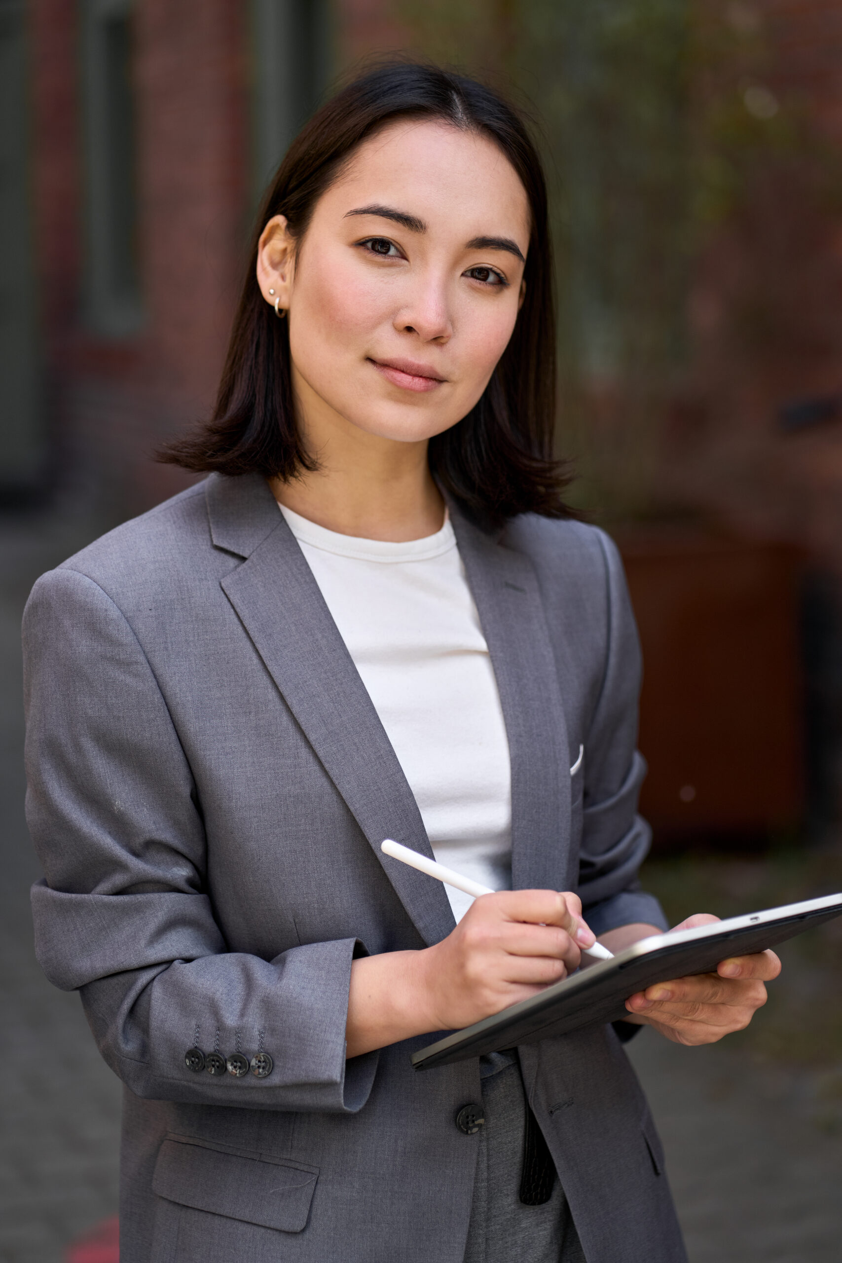 Young confident Asian business woman entrepreneur holding tablet, portrait.